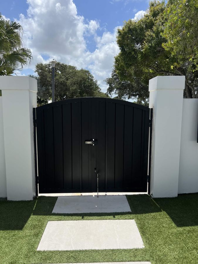 Tall black privacy gate with paver walkway