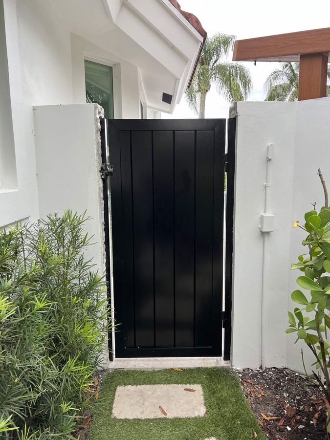 Black side yard privacy gate between stucco walls