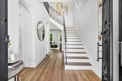 White staircase with slim black metal railing in a modern foyer